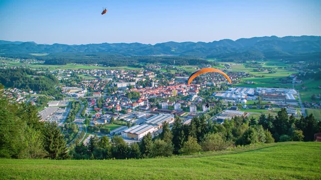 Three paragliders fly over Slovenj Gradec city, Slovenia. Slow motion