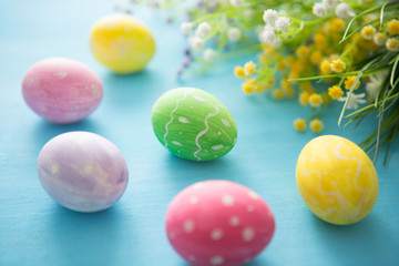 Colorful easter eggs with flowers on a blue wooden table background
