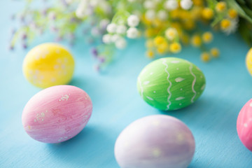 Colorful easter eggs with flowers on a blue wooden table background