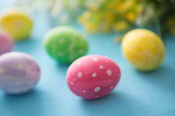 Colorful easter eggs with flowers on a blue wooden table background