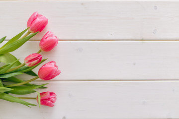 Bouquet of pink tulips on white wooden background. Top view, copy space