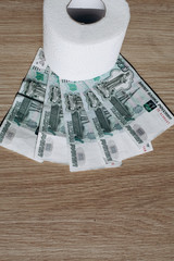 Several banknotes with a face value of 1000 rubles and a roll of toilet paper