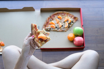 Woman hand holding pizza eating with orange on floor background, Bahrain