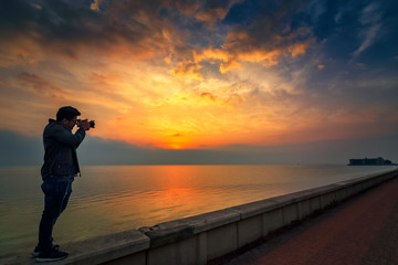 An adventure photographer sightseeing in Khobar sea side sunrise background. City : Khobar/ Saudi Arabia.