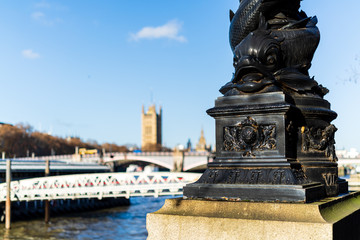 Obraz premium London, England - November 29 2019 : Lamp post base of fish on Thames riverside with houses of parliament blurred in background, in London, England