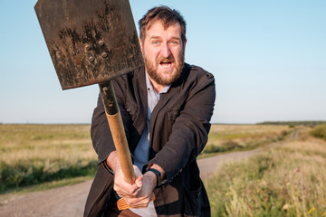 angry white bearded man is swinging a shovel