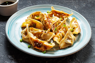 Japanese gyoza or dumplings snack with soy sauce on black stone background