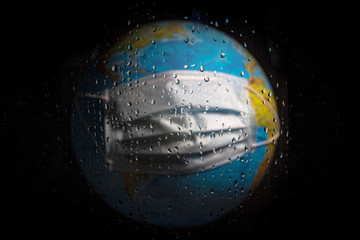 Horizontal photo of planet Earth through wet glass with drops. The concept of weather or isolation after a coronavirus pandemic.