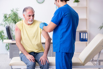 Injured old man visiting young male doctor traumatologist