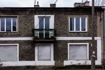 Old abandoned house.The main facade. Balcony, brick and plaster, locked windows. Good material for a site about disasters, construction, architecture.