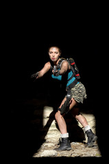 A young girl is dressed up in a semi military outfit. She  is seen in a dark run down urban area. She has  weapons with her for self defense reasons.