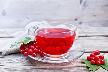 Tea from viburnum in cup with berries on gray wooden board