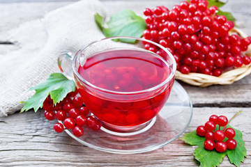 Tea from viburnum in cup with berries on old board