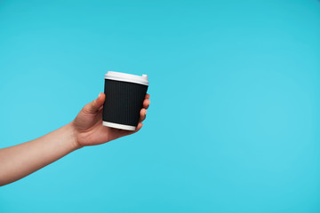 Photo of black paper cur with coffee being held by young female with white manicure, suggesting hot...