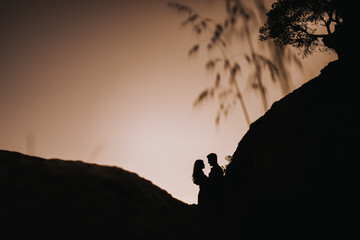Couple silhouette enjoying romantic colorful sunset in love