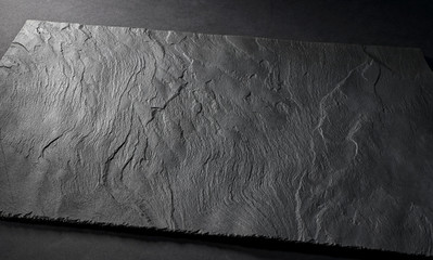 black matte slate natural stone plate with textured surface on gray background