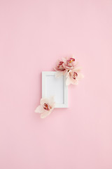 photo frame decorated with orchid flowers on pink pastel background. empty space for text. mock up with copy space. Flat lay