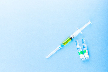 Syringe with injection vaccine on a blue background.