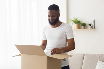 African american guy looks at purchase in box and smiles