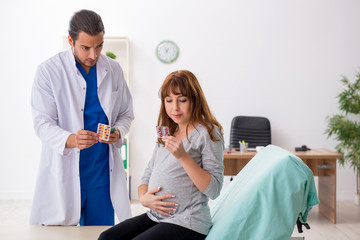 Obraz premium Young pregnant woman visiting male doctor gynecologist