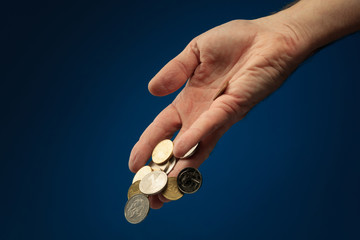 The concept of falling revenue/income. Various coins from around the world held in hand. Coins...