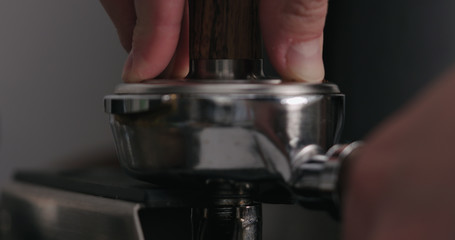 man tamping freshly ground coffee closeup