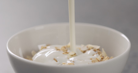 closeup granola with almond flakes poured with yogurt