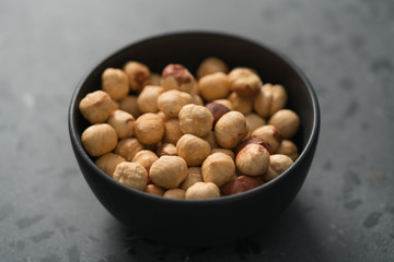 roasted hazelnuts in black bowl on terrazzo countertop