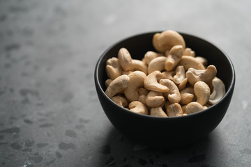 roasted cashew in black bowl on terrazzo countertop