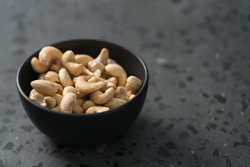 roasted cashew in black bowl on terrazzo countertop
