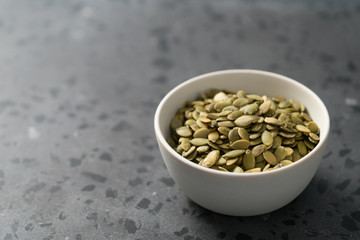 pumpkin seeds in white bowl on terrazzo countertop