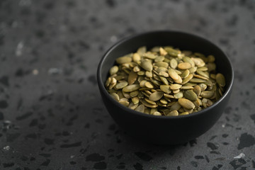 pumpkin seeds in black bowl on terrazzo countertop