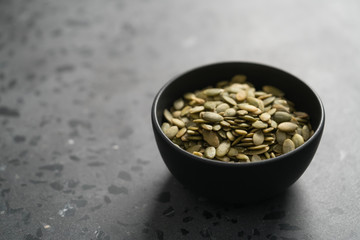 pumpkin seeds in black bowl on terrazzo countertop
