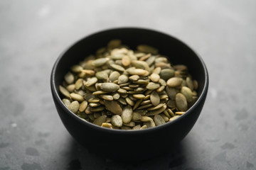 pumpkin seeds in black bowl on terrazzo countertop