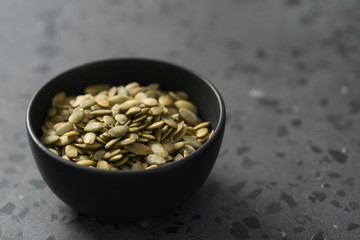pumpkin seeds in black bowl on terrazzo countertop
