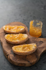 Naklejka na ściany i meble Ciabatta slices with orange marmalade on olive board