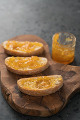 Fototapeta na wymiar Ciabatta slices with orange marmalade on olive board