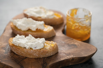 Ciabatta slices with orange marmalade and ricotta on olive board