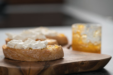 Ciabatta slices with orange marmalade and ricotta on olive board