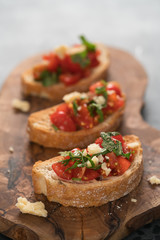 bruschetta with cherry tomatoes, spinach leaves and hard cheese on olive board