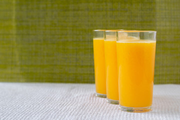 Orange juice in a glass with orange decoration, the best start to the day. Photo on a green background.