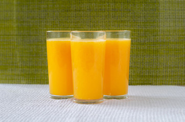 Orange juice in a glass with orange decoration, the best start to the day. Photo on a green background.