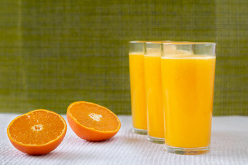 Orange juice in a glass with orange decoration, the best start to the day. Photo on a green background.