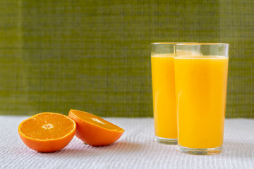 Orange juice in a glass with orange decoration, the best start to the day. Photo on a green background.