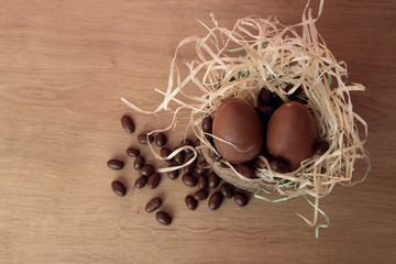 Chocolate Easter Eggs in wicker basket with candy on wooden background