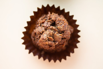 Chocolate corn flake cake in brown paper cupcake case. Close up of sweet dessert with gold dust sprinkles. Simple party cake recipe for children