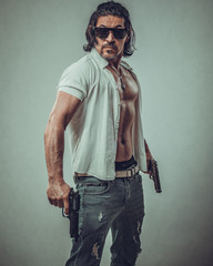 sexy muscular body model portrait of a young man holding a gun in his hands