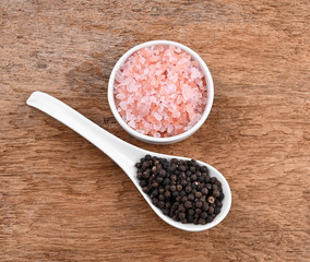 bowl of pink himalayan salt , Black pepperon  wooden table, top view