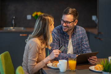 Beautiful smiling young couple having breakfast at home