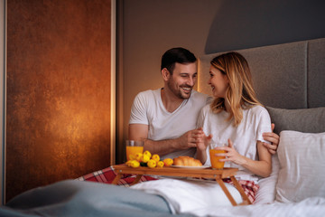 Obraz na płótnie Canvas Happy couple having a breakfast in the bed